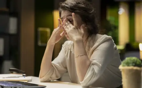 Eine Frau reibt sich erschöpft die Augen, die Arbeit am Laptop ist zu viel. Ich kann nicht mehr.
