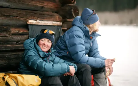 Zwei Personen in warmen 700 cuin Daunenjacken genießen eine Pause im Freien. Die Jacken halten sie bei kühler Temperatur angenehm warm.