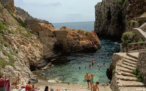 Santa Maria di Leuca: cosa vedere? Una caletta rocciosa con gente che nuota e si rilassa, con scalinate di pietra che scendono verso il mare cristallino.