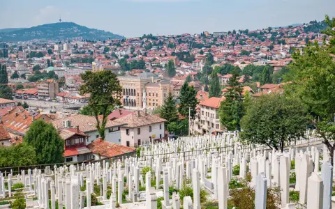Widok na cmentarz z białymi nagrobkami i panoramę Sarajewa. Warto zobaczyć to miejsce, by poczuć historię miasta.