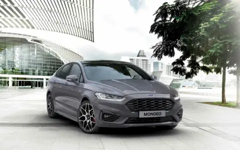 Ford Mondeo gris aparcado frente a un edificio moderno. Las medidas del Ford Mondeo son ideales para la ciudad.