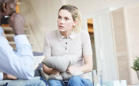 Kobieta w trakcie sesji u psychiatry, ściska poduszkę, szukając ukojenia.