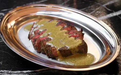 Tranché de bœuf, nappé d'une sauce verte, une spécialité parisienne servie sur un plateau métallique.