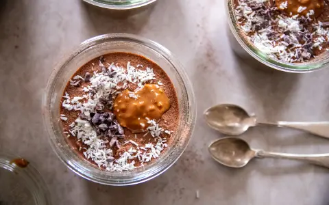 Chokladpudding med kokos och kakaonibs, en härlig proteinrik frukost. Två skedar ligger bredvid.