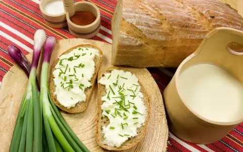 Chleb z twarogiem i szczypiorkiem, obok mleko i cebulka. Idealne składniki na zaprawę do wyrobu bryndzy.