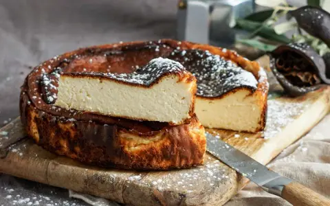 Tarta de queso La Viña, receta auténtica con su interior cremoso y exterior caramelizado, espolvoreada con azúcar glas.
