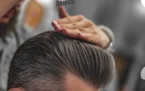 Stylista układa włosy, pokazując, jak mieć gęste włosy chłopak.