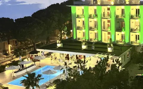 Hotel Biondi Cesenatico: piscina illuminata e facciata verde brillante. Le recensioni lodano l'atmosfera serale.