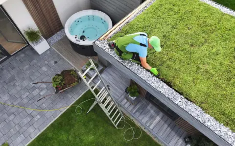 Pracownik pielęgnuje zielony dach, przykład **powierzchni biologicznie czynnej definicji**. Obok jacuzzi i taras.