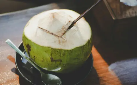 Une noix de coco verte ouverte avec une paille, prête à déguster. Découvrez les nombreux bienfaits de l'eau de coco pour une hydratation naturelle.