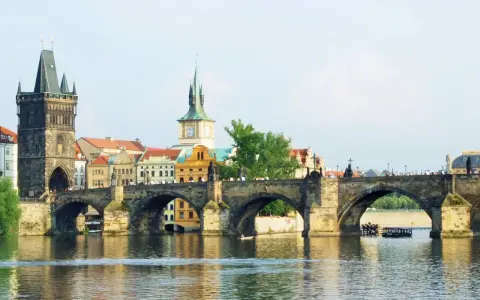 Most Karola w Pradze, z wieżą i zabytkowymi budynkami. To piękne informacje o Czechach.