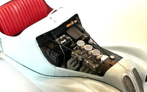 Detailansicht eines Modellautos mit rotem Lederinterieur und detailliertem Motor, dessen Teile mit Chromfolie veredelt sind.