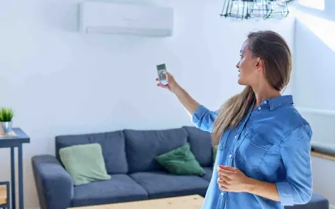 Mujer ajustando el sistema de climatización con un control remoto.