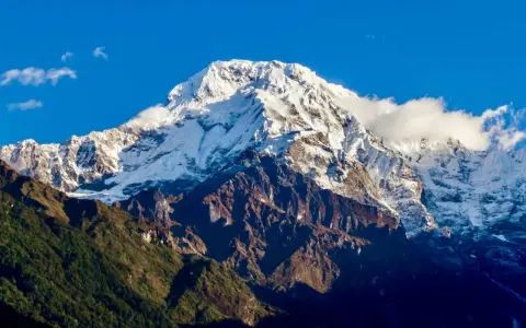 Majestatyczny szczyt w Himalajach 8091 m, pokryty śniegiem, góruje nad zielonymi zboczami.