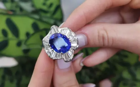 Anello con una preziosa pietra azzurra al centro, circondata da diamanti a baguette e taglio brillante.