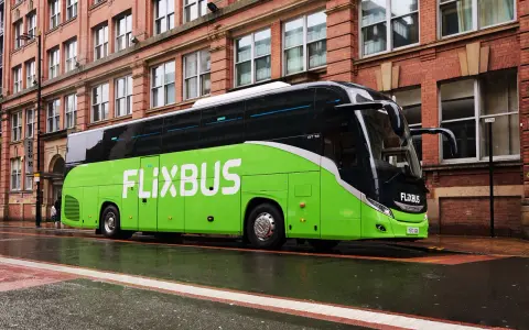Zielony autokar FlixBus na mokrej ulicy. Wiele osób chwali sobie podróże tymi autobusami, a flixbus opinie są zazwyczaj pozytywne.