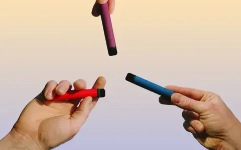 Manos sostienen vapers de colores: rojo, azul y morado. Una opción para un vaper sano.