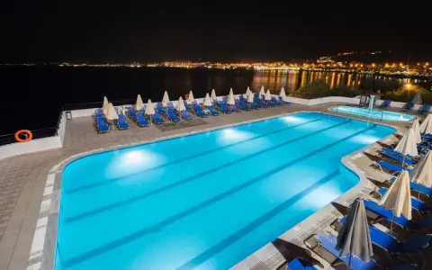 Basen hotelowy nocą, z widokiem na oświetlone miasto na horyzoncie. Idealne miejsce na relaks, jak sugerują pozytywne opinie o horizon beach.