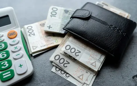 Portfel z polskimi banknotami i kalkulatorem. Nowa praca to szansa na lepsze zarobki.