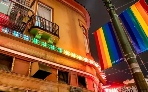 Rainbow flags fly proudly in the gayest city in America, illuminating a building with colorful lights.