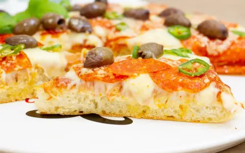 Pyszna pizza z patelni z pikantnym salami, oliwkami i papryczką. Idealna na szybki obiad.