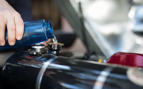 Maintenir le moteur 4 temps en bon état : on verse du liquide de refroidissement bleu dans le réservoir.