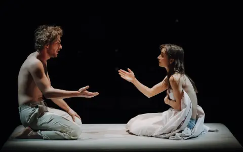 Aktorzy na scenie Teatru Narodowego, w intymnym geście, jakby dzielili się ostatnim tchnieniem.