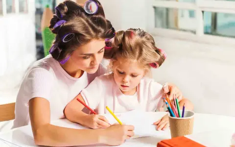 Mama i córka z wałkami na włosach rysują kredkami. Wspaniałe zabawy dla dzieci w domu 10 lat i młodszych.