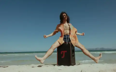 Mężczyzna na plaży skacze na głośniku, słuchając stare piosenki na lato.