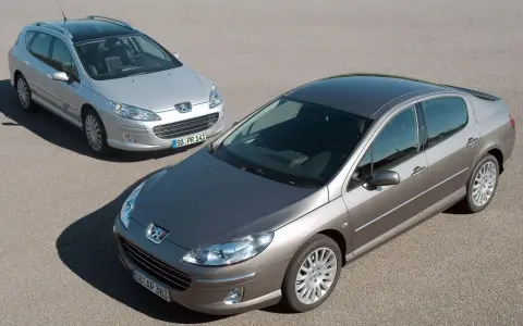 Dwa samochody Peugeot 407, sedan i kombi, na drodze. Wiele osób chwali sobie te modele, a opinie o Peugeot 407 są zazwyczaj pozytywne.