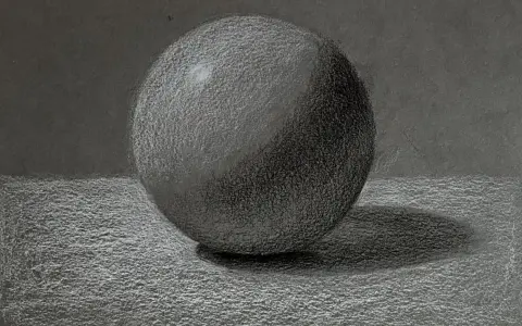 Un detallado dibujo a carboncillo de una esfera, con luces y sombras que le dan volumen. La textura del papel se aprecia en este estudio de esfera.