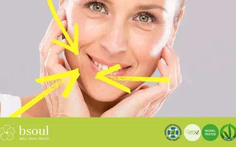 Primo piano di un volto femminile con rughe d'espressione, evidenziate da frecce gialle. Il trucco leggero esalta la bellezza naturale.
