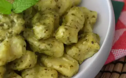En skål med krämig italiensk gnocchi med pesto, toppad med färsk mynta. Ett perfekt italiensk gnocchi recept för en snabb och god middag.