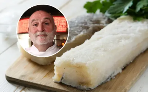 Chef sonriente junto a trozos de bacalao en salazón sobre tabla de madera.