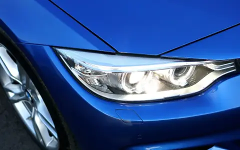 Blå BMW-strålkastare, redo för prewash. En del av en sportig bil med blanka fälgar.
