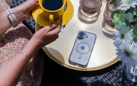 Eleganckie etui przezroczyste z wzorami na telefon, leżące obok żółtej filiżanki kawy i białych kwiatów.