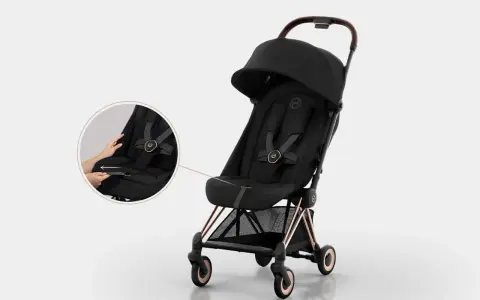 Elegancki czarny wózek Cybex Coya z miedzianymi detalami. Widoczna lupa pokazuje łatwe zapinanie pasów.