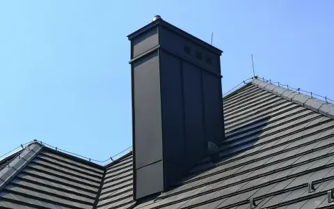 Nowoczesna obróbka blacharska komina na dachu z dachówki. Schemat montażu zapewnia estetykę i trwałość.