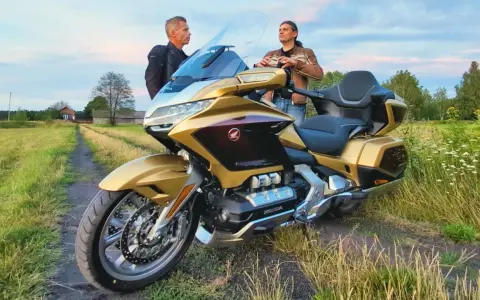 Złoty Honda Goldwing 1800 na polnej drodze, dwaj mężczyźni dyskutują o jego wadach.