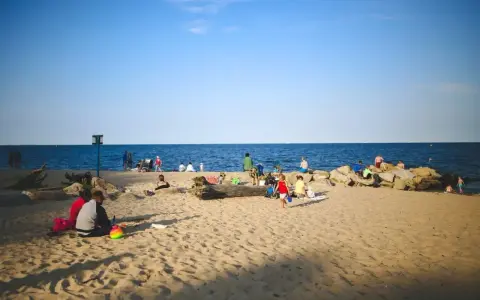 Ludzie odpoczywają na plaży, ciesząc się słońcem i morzem. Widać, ile Szczecin ma do morza – bliskość natury i relaks.