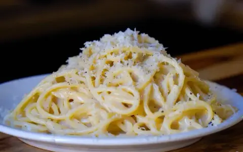 Pyszne cacio e pepe, czyli spaghetti z serem i pieprzem, posypane startym parmezanem.