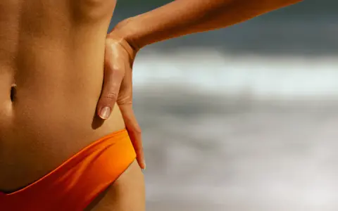 Brązowa opalenizna po ilu dniach czerwona opalenizna brązowieje? Słońce na plaży podkreśla gładką skórę.