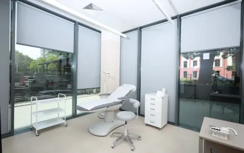 Gabinet dermatologiczny z fotelem zabiegowym, szafką i wózkiem.