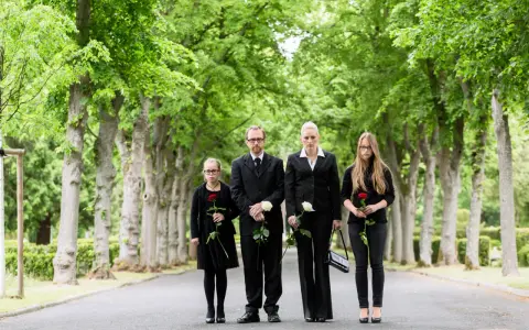 Rodzina w czarnych strojach, trzymająca róże, pokazuje, jak się ubrać na pogrzeb. Elegancko i z szacunkiem.