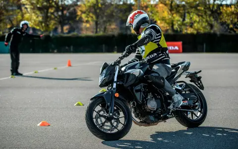 Motociclista con equipo de protección en una pista de examen con conos.