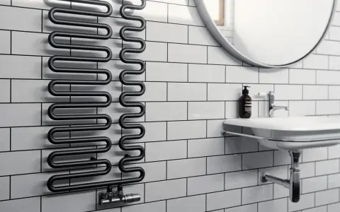 Radiador toallero negro con diseño ondulado, ideal para secar toallas o calentar el baño. Un radiador normal con estilo.