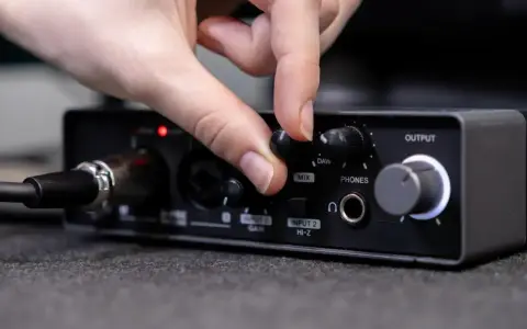 Dłoń reguluje pokrętło miksu na interfejsie audio, przygotowując wyjście liniowe do pracy.