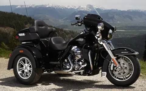Harley-Davidson negro de tres ruedas aparcado en un paisaje montañoso. Recuerda que las motos de tres ruedas necesitan carnet de moto.