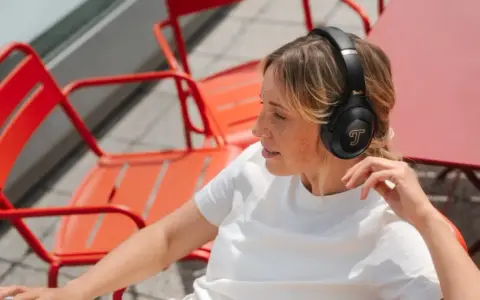 Femme aux taches de rousseur écoutant de la musique avec des écouteurs, un exemple de 85 dB pour une immersion sonore.
