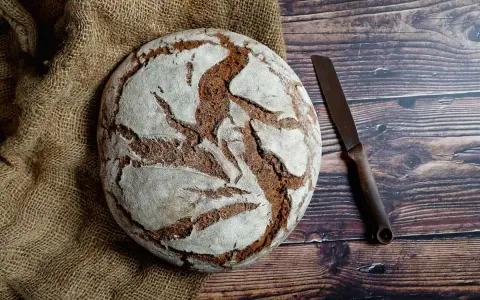 Pan casero rústico sobre arpillera, listo para cortar con un cuchillo. Una delicia para tu receta de pan casero.